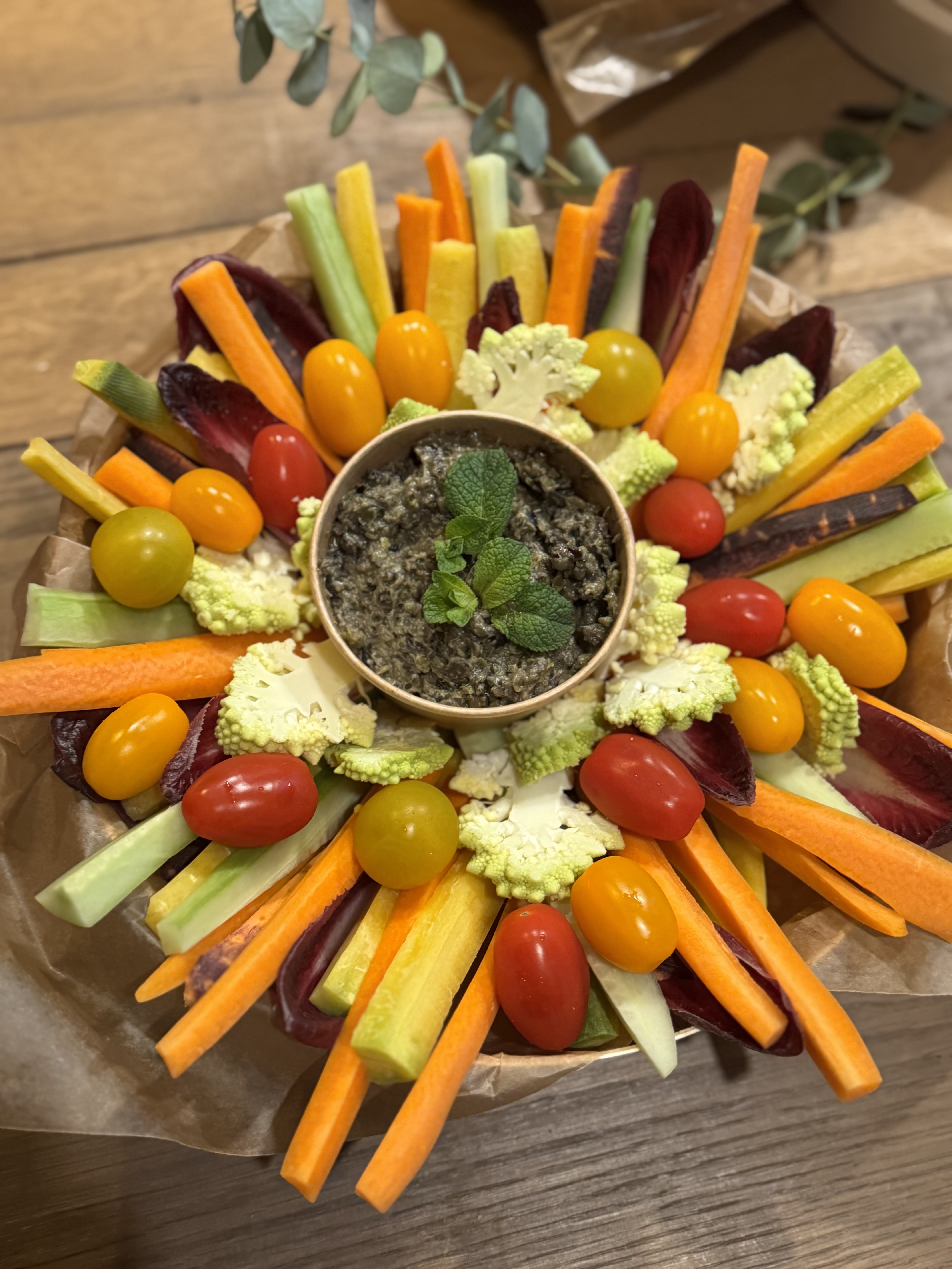 Plateau de légumes crus colorés autour d'une tapenade