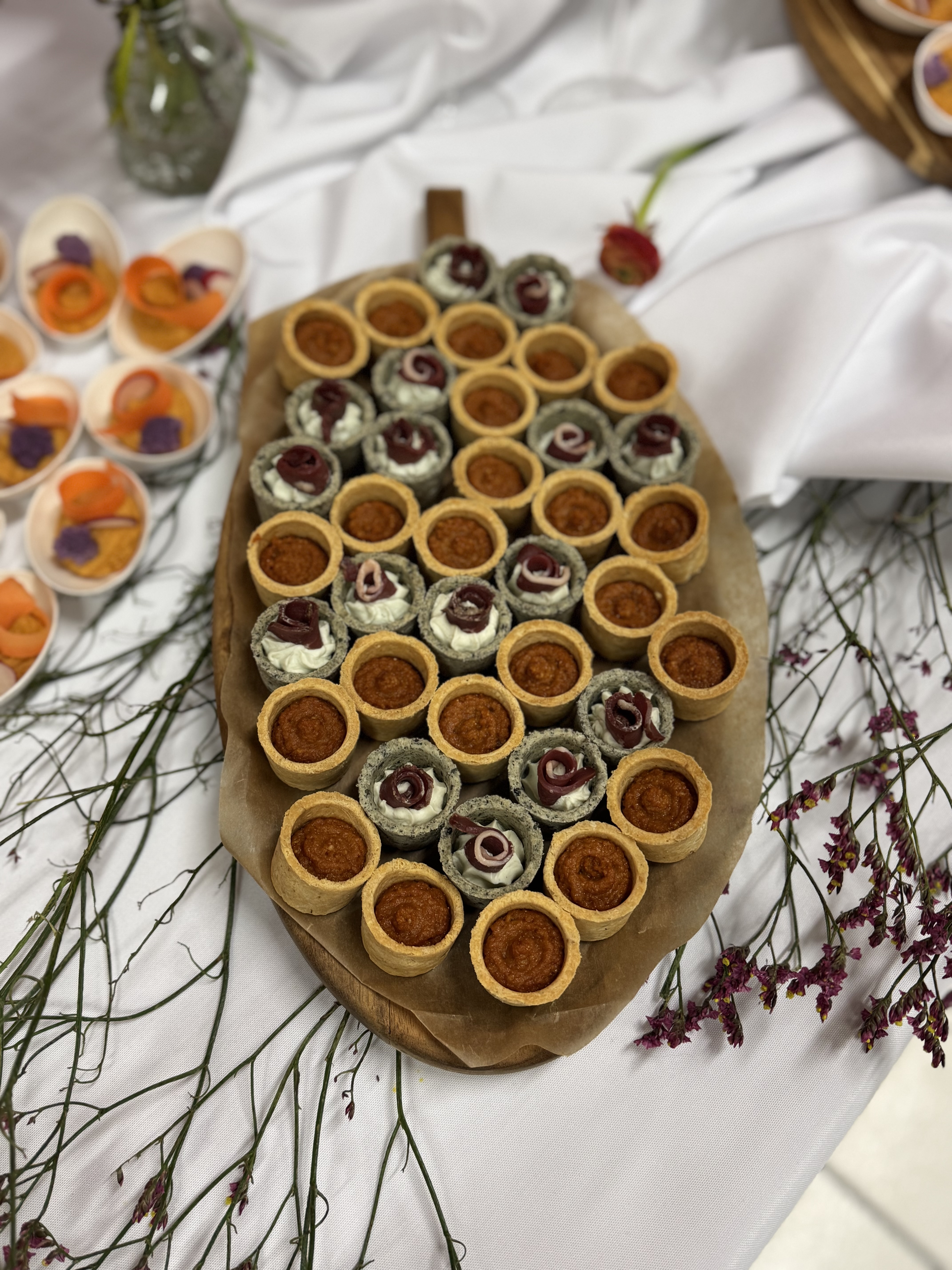 Plateau de mini-tartelettes salées sur planche bois et fleurs séchées